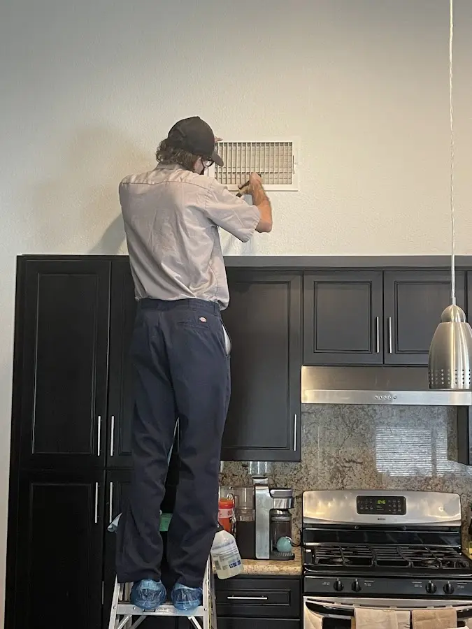 Technician inspecting an air vent during HVAC service in East Windsor